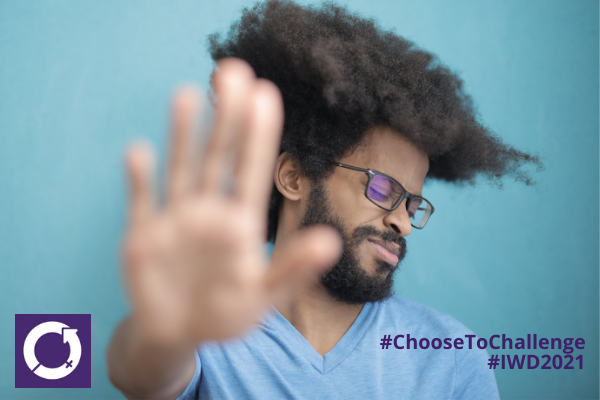 A black man holding up his hand as if to say 'stop' with the hashtag #ChooseToChallenge and #IWD2021