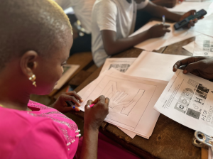 Close up of a girl from Sierra Leone rawing out 'N' for 'No' from the A-Z