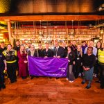 Representatives from the night-time economy standing with the purple flag in a bar.