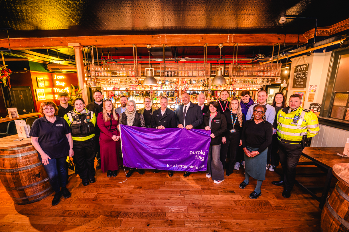 Representatives from the night-time economy standing with the purple flag in a bar.