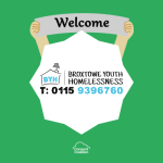 An 8 pointed white star with the Broxtowe Youth Homelessness logo in the centre. Coming out from the top of the star are two hands holding up a 'welcome' banner. Behind all this the background is green, the Consent Coalition logo is in white below the star